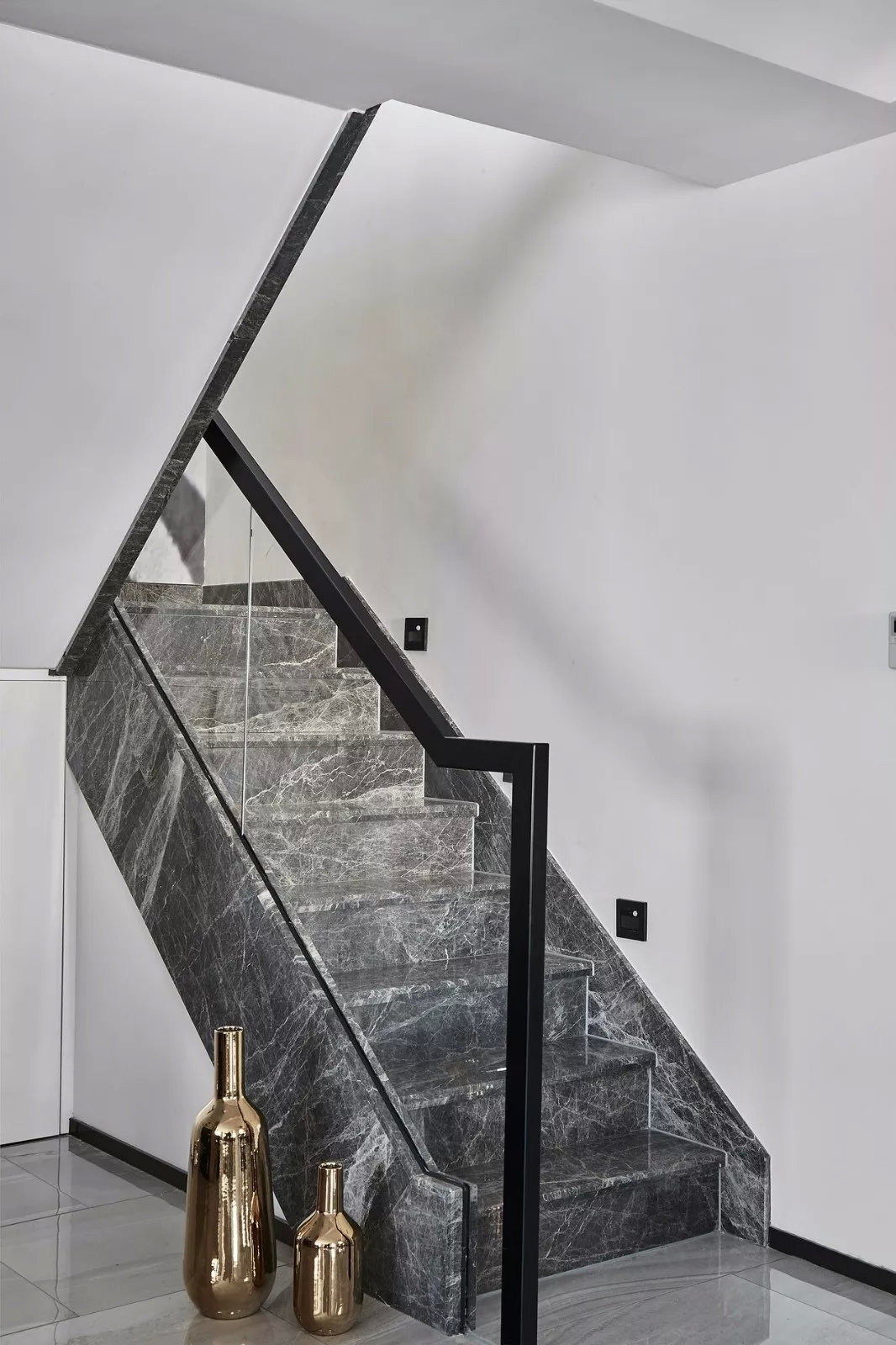 整个楼梯采用深灰色大理石铺贴,玻璃护栏加上黑色金属扶手,低调且奢华