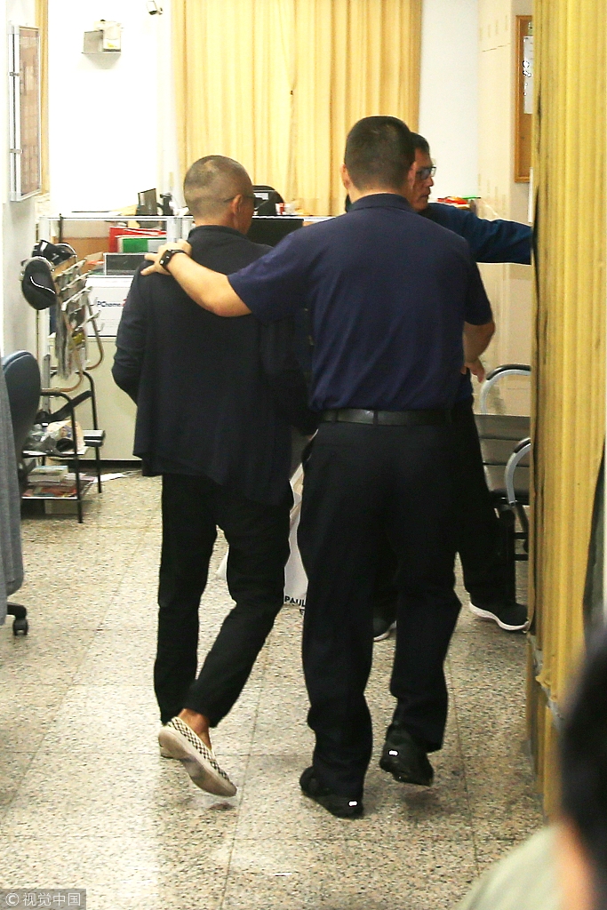 导演钮承泽剃光头背帆布包赴警局应讯 面对媒体一路沉默