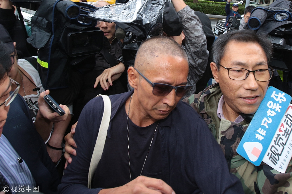 导演钮承泽剃光头背帆布包赴警局应讯 面对媒体一路沉默