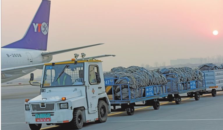 在西安咸阳国际机场货机坪,航空物流公司工作人员正驾驶行李牵引车驶