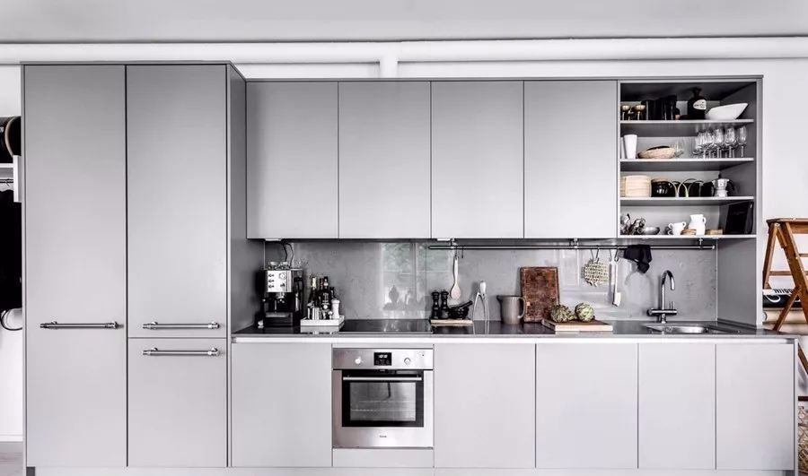 靠墙的厨房是一套浅灰色厨柜,灰色的台面和背板.
