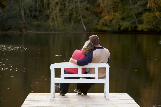 couple sitting on a bench at a lake in autumn