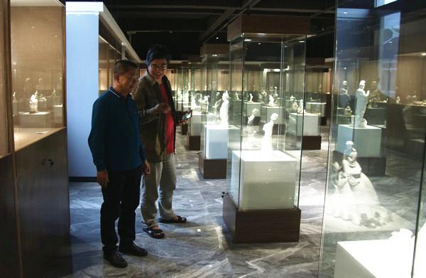 曾镇溪(右)在德化陶瓷大师博物馆内观摩陈列作品