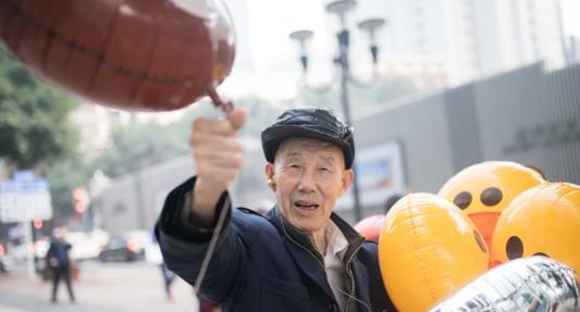 重庆76岁老人带着助听器街边卖气球,一站就是一天!