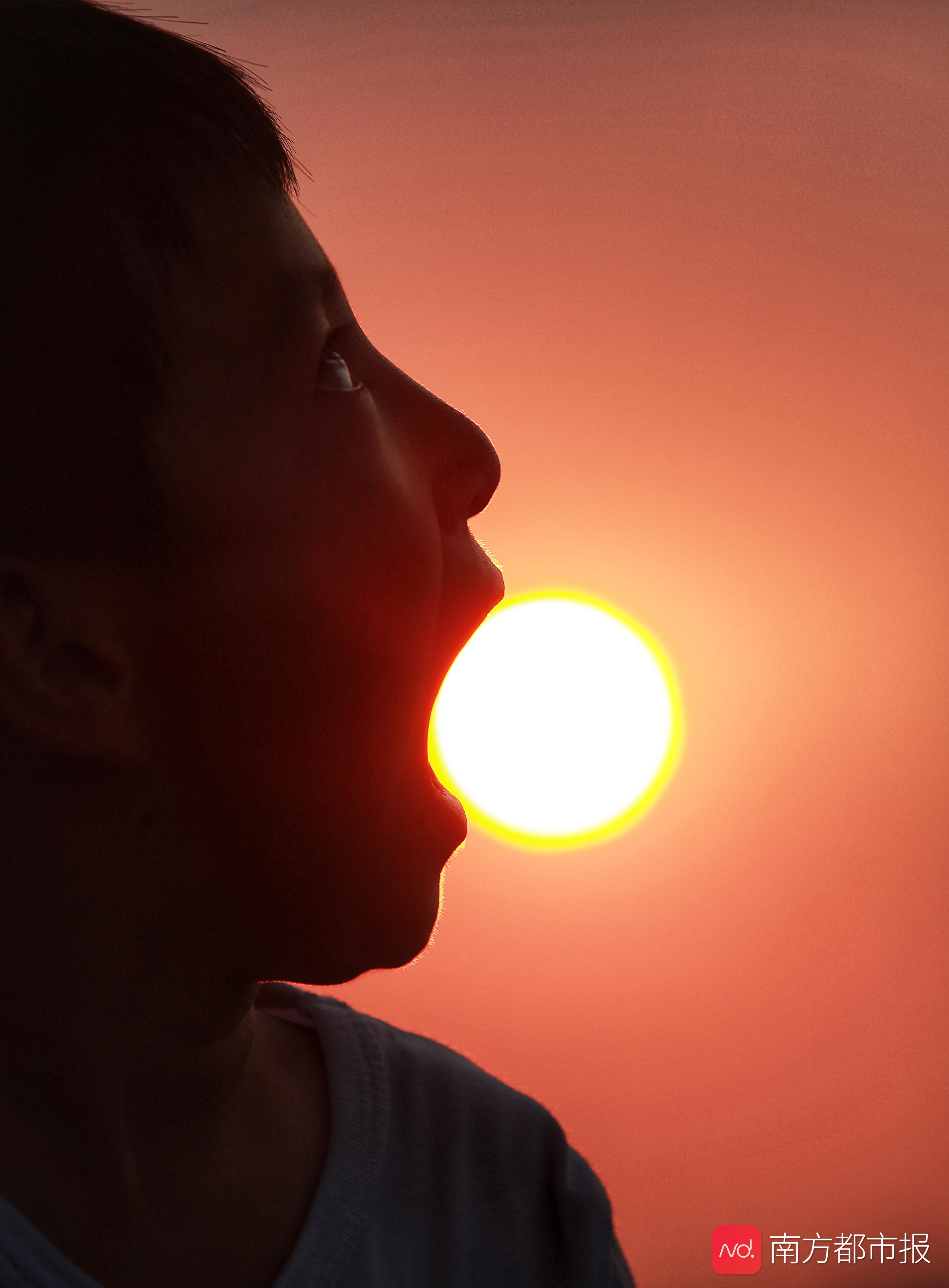 广州一位小朋友张大嘴巴,拼尽全力要吞下落日的样子